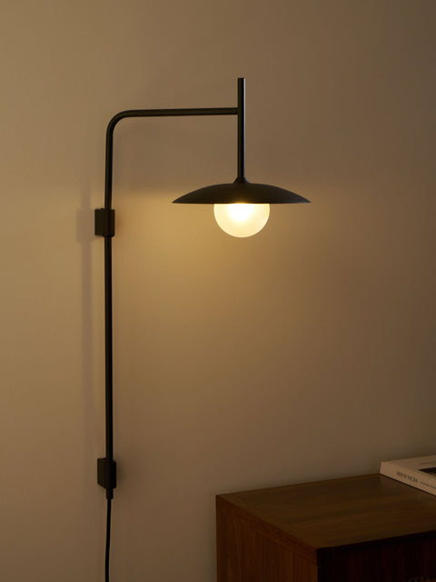 Wall Lamp with Swing Arm and Glass Globe Beneath a Metal Shade