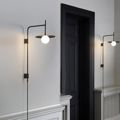 Wall Lamp with Swing Arm and Glass Globe Beneath a Metal Shade
